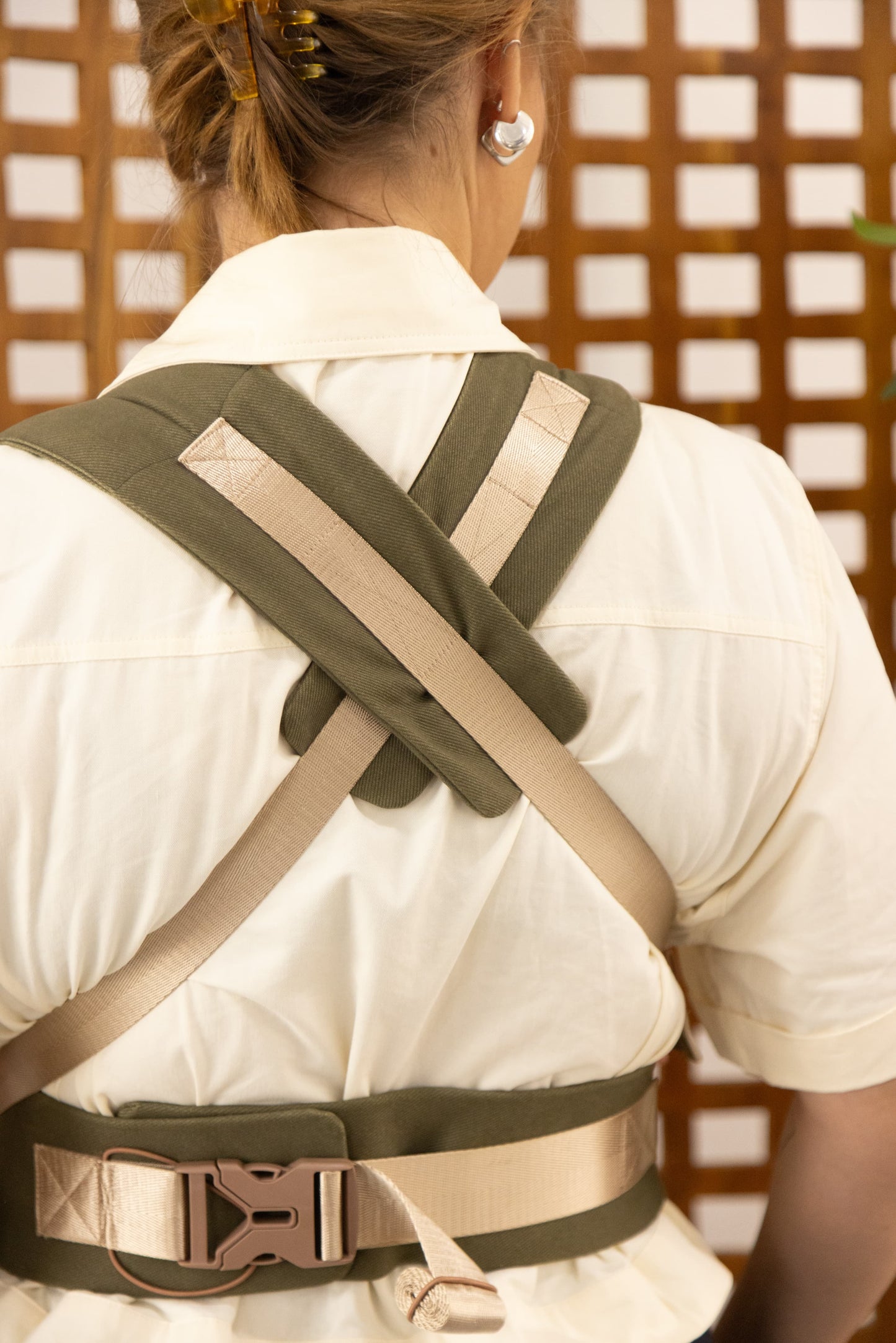 Person wearing a green and beige back brace against a wooden lattice background
