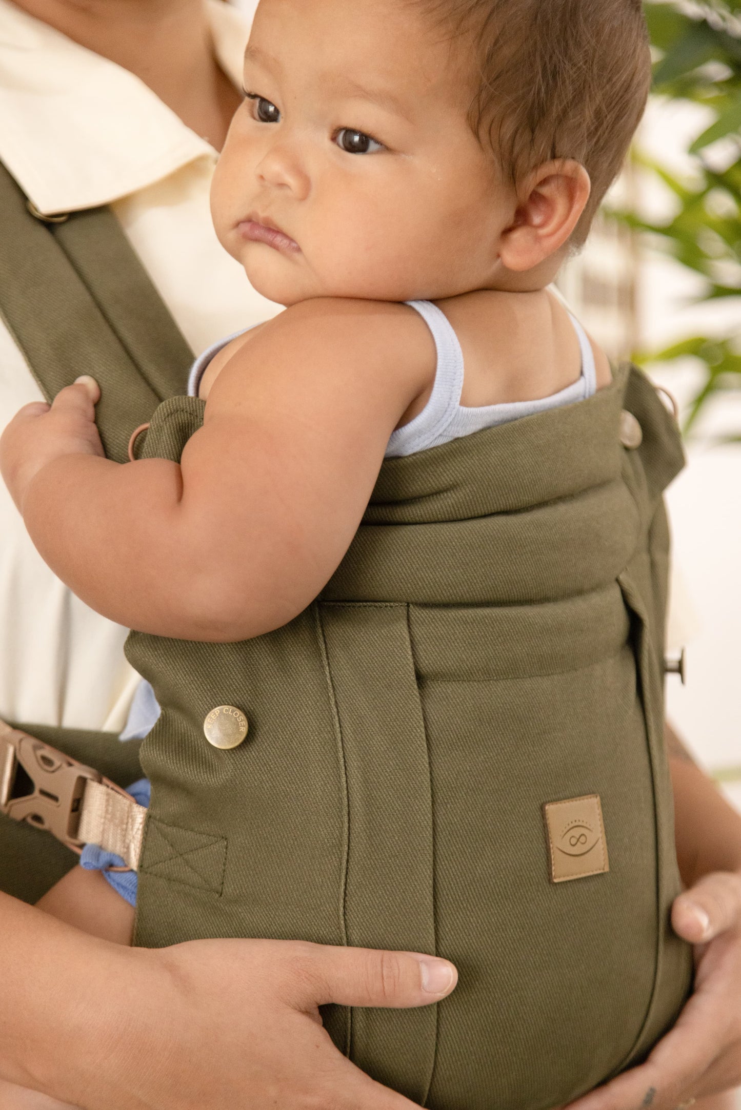 Baby in a green carrier with a blurred background