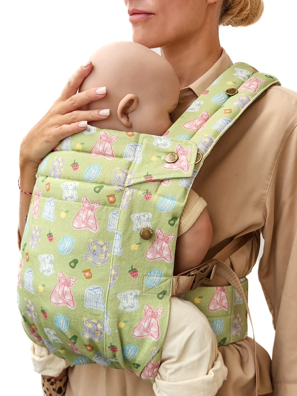 Person wearing a custom designed green baby carrier with cartoon designs on a plain background