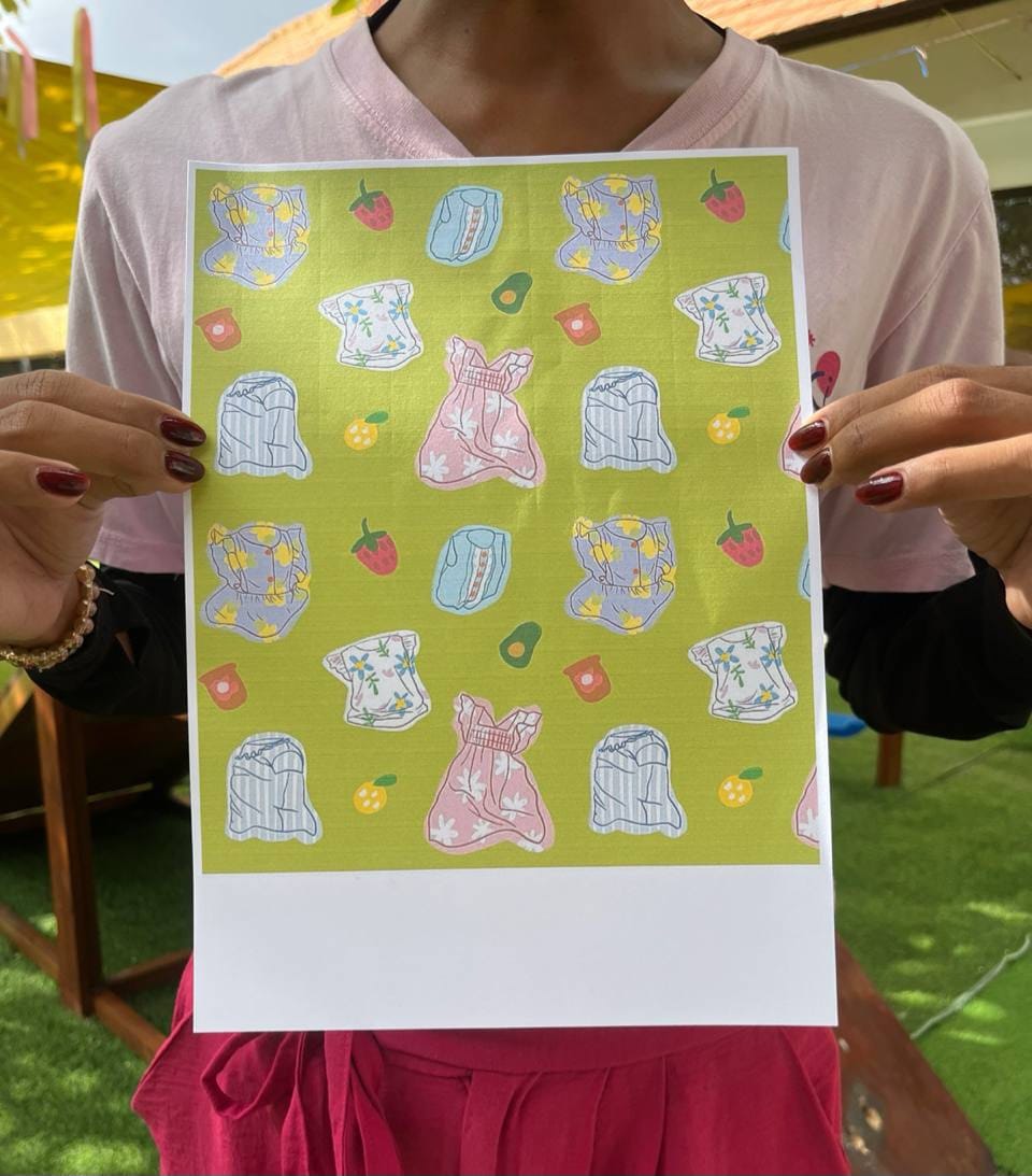 Person holding a sheet of paper design illustrations on a green background