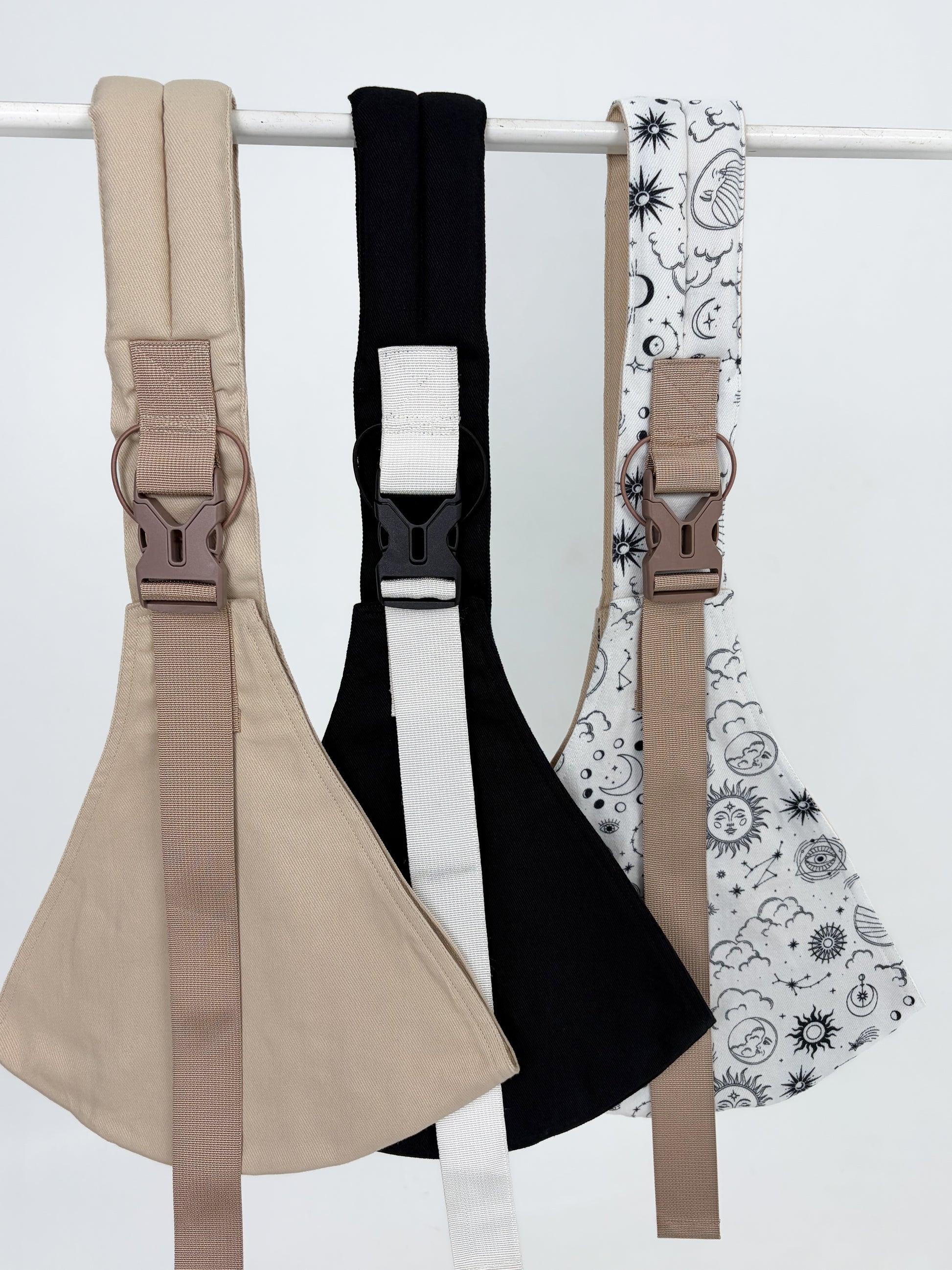 Keep Closer toddler hip carriers displayed in three colours: sand, black, and Sun and Moon print